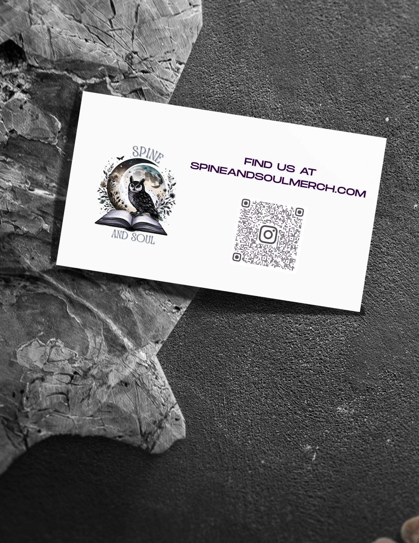 White business card with logo and QR code on a textured black surface